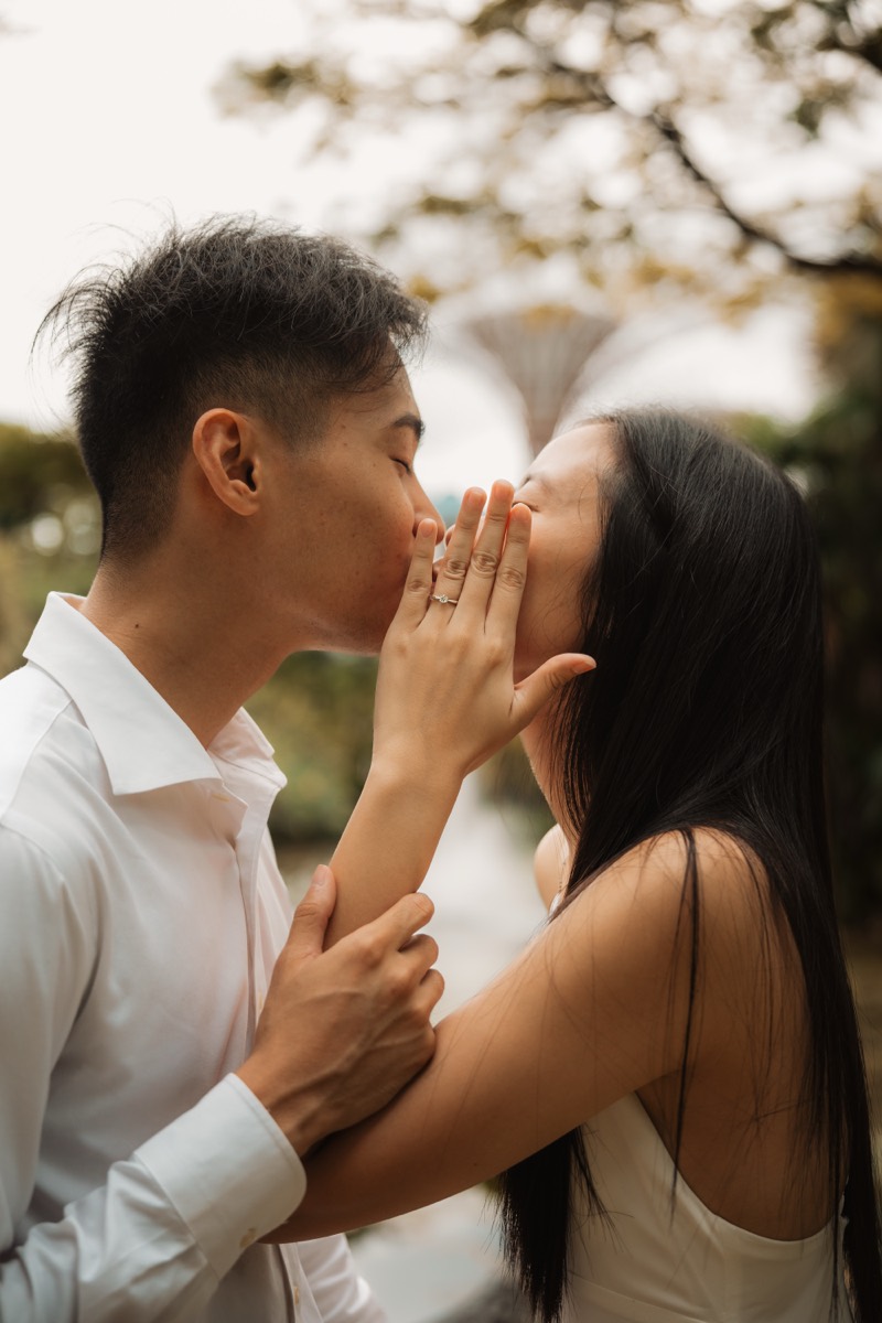 A couple kiss in profile, the Supertrees rising softly behind them.