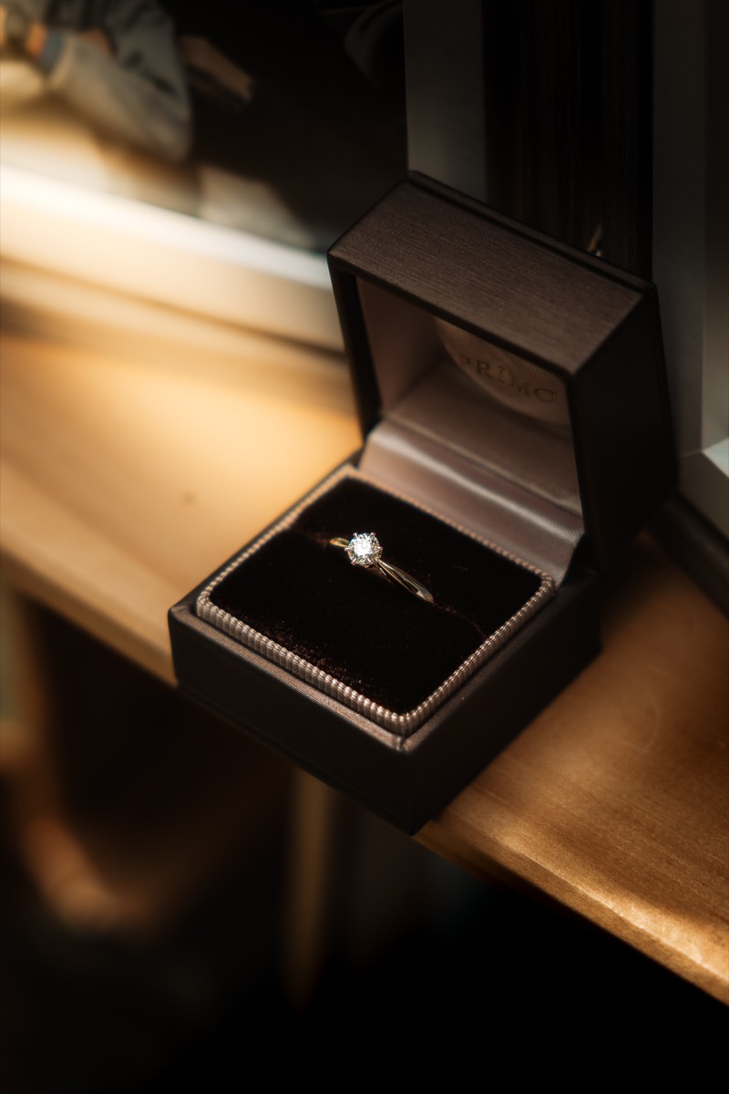 An engagement ring resting in its open box, lit low and warm.