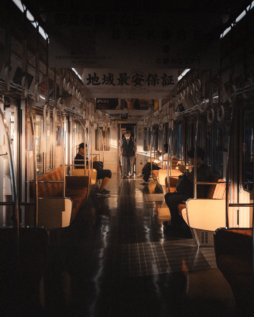Last Carriage — a lone figure stands in a warm-lit train carriage at night.