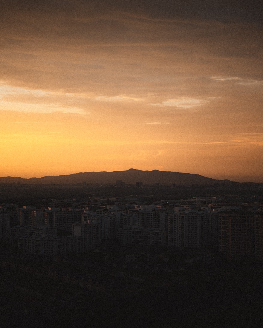 City at Dusk — an orange sky glows over a distant, hazy city skyline.